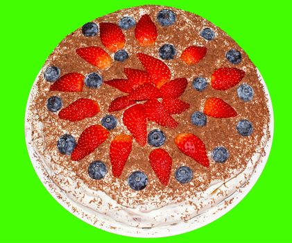 
Round cake on a green background with strawberries and blueberries.