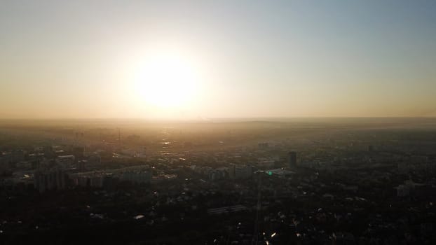 Bright yellow sun over the city of Almaty. Strong gas pollution from cars gives an unusual appearance to the city. Shadows from houses, tall buildings. Cars drive on wide roads. Peace and beauty.