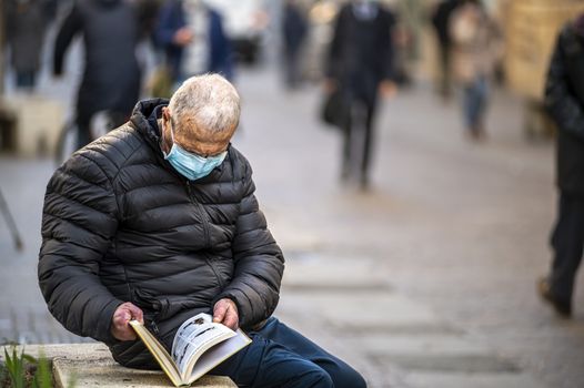 terni,italy november 19 2020:man with medical mask reads a book outdoors