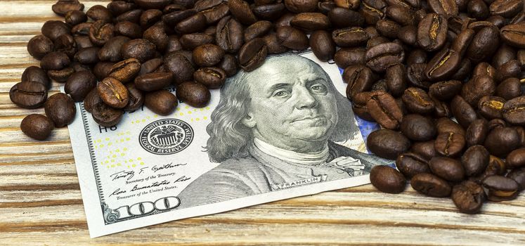 On a wooden background is a money bill and coffee beans