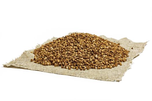 Buckwheat groats lie on a cloth napkin on a white background