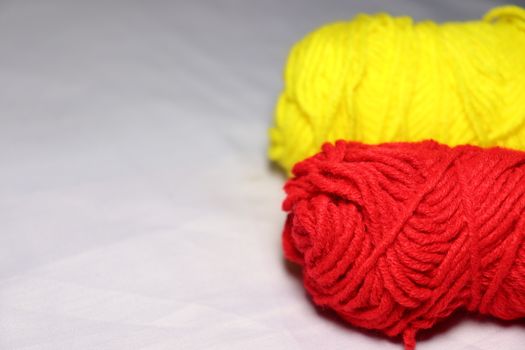 red and yellow colored yarn closeup on white background