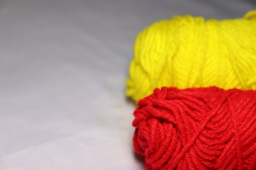 red and yellow colored yarn closeup on white background