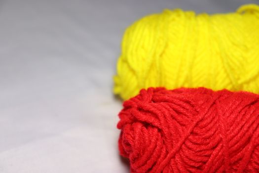 red and yellow colored yarn closeup on white background