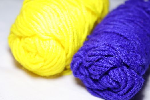 blue and yellow colored yarn closeup on white background