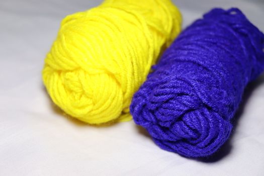 blue and yellow colored yarn closeup on white background