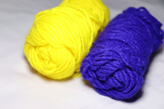blue and yellow colored yarn closeup on white background
