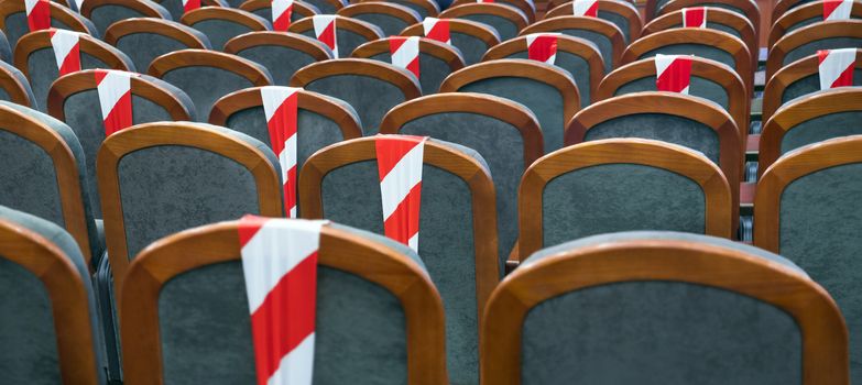 Social distancing during the crisis of Covid, coronavirus. Keeping your distance during a show, concert or play in a theater or cinema, conference hall. Empty rows of places marked with a warning tape