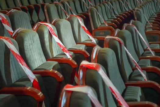 Keep your distance to avoid physical contact. Practice of social distancing. View of rows of seats marked with a warning tape in the cinema, theater, auditorium, conference hall. Protection COVID-19