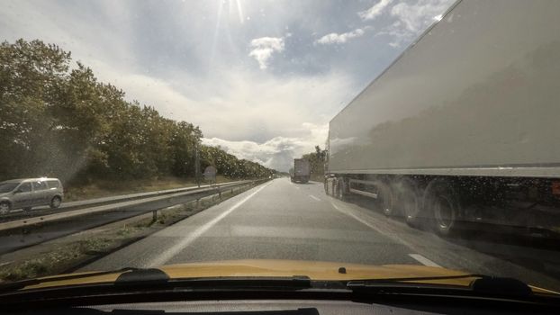 Driving on a highway point of view and overtaking a truck, raindrops on the windscreen