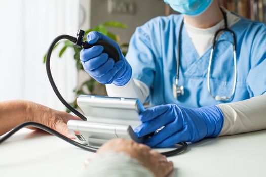 Doctor checking patient blood pressure using manual inflation blood pressure monitor (sphygmomanometer), routine check up to determine systolic and diastolic pressure, hypertension diagnosis treatment