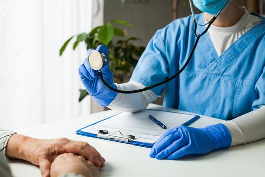 General Practitioner in doctor's office, physician performing a blood pressure checkup, listening to patient's heart, lungs and intestines with stethoscope, prevention and healthy lifestyle concept