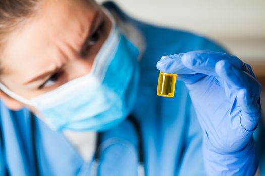 Medical worker inspecting ampoule vial bottle filled with yellow liquid,COVID-19 potential vaccine cure develop,convalescent patient platelet rich blood plasma transfusion,Coronavirus therapy concept