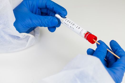 Coronavirus COVID-19 testing kit,swab collection equipment,sterile vacutainer with swabbing stick,closeup of hands in blue protective gloves holding the test tube,rt-PCR sample specimen testing