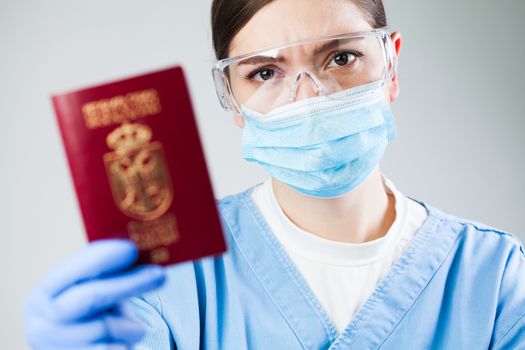 Doctor or nurse at airport customs security check holding a passport, no entry quarantine and isolation order ban, COVID-19 virus disease epidemic, viral Coronavirus global worldwide pandemic outbreak