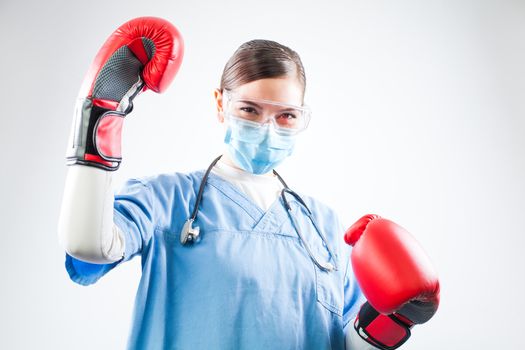 Coronavirus COVID-19 corona virus disease pandemic outbreak,female doctor wearing red boxing gloves,arm raised in air,victory over invisible enemy,happy victorious medical healthcare professional