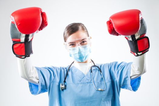 Victorious young female caucasian GP doctor wearing blue uniform red boxing gloves,hands raised in air, satisfied and happy after patient surviving disease and recovering, isolated on white background