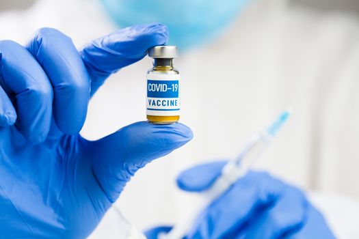 Coronavirus COVID-19 vaccine development,research for cure & treatment of infected patients,groundbreaking discovery in battle against SARS-CoV-2 pathogen,hands in gloves holding ampoule & syringe jab