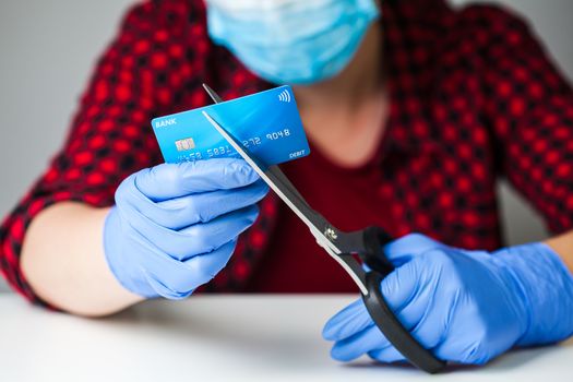 Coronavirus COVID-19 corona virus disease global pandemic outbreak causing world economy recession and market crash,caucasian female person cutting bank card with scissors,financial hardship concept