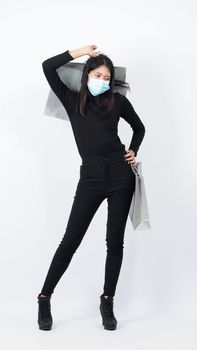 Asian woman holding shopping bags in her hand and wearing medical face mask to protect coronavirus or Covid 19 that is pandemic virus which represent shopper in new normal situatiuon and shop lover.