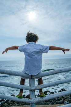 Child relaxing on the beach by opening arms against the background of sea and sky . Summer vacation and travel concept