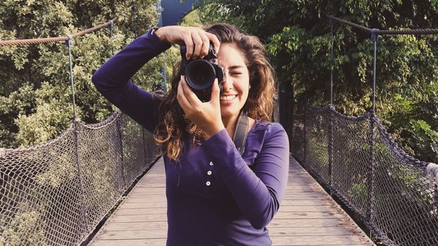 Outdoor summer smiling lifestyle portrait of pretty young woman having fun in the city of Lima taking pictures with her camera