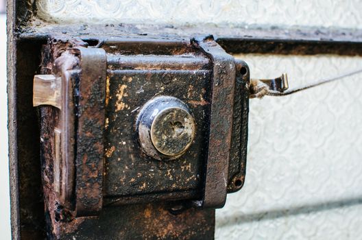 Old metal lock latch and a glass door bar