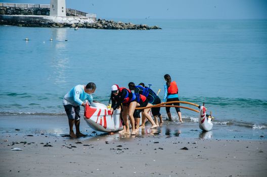 A group of boys paddlers pulling a boat towards the shore