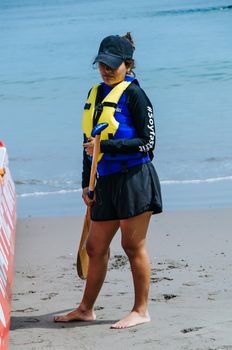 Young woman paddler smiling with an oar in hand at the seashore