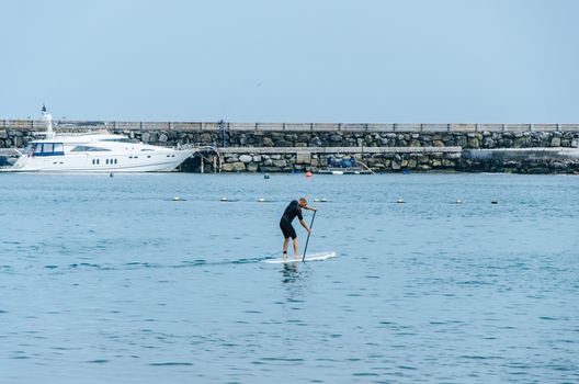 Stand up paddle board man paddleboarding on Peruvian beach standing happy on paddleboard on blue water. Summer holidays vacation travel.