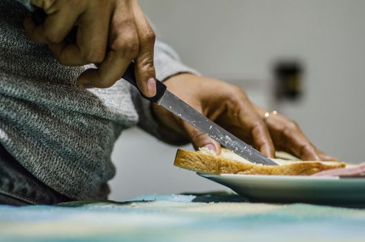 Male hands cutting wheaten bread on the wooden board, selective focus