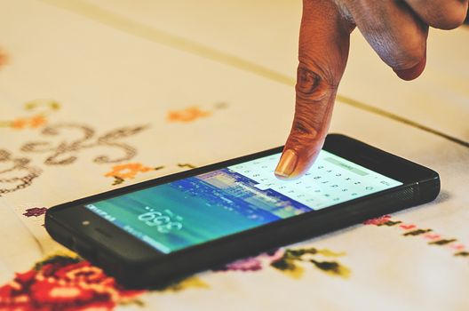 Finger touching the screen of a smartphone, on a table
