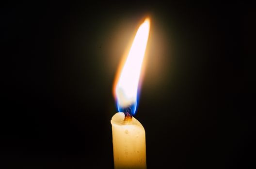 Old candle melting and shining in the darkness