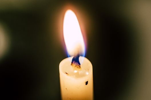 Old candle melting and shining in the darkness