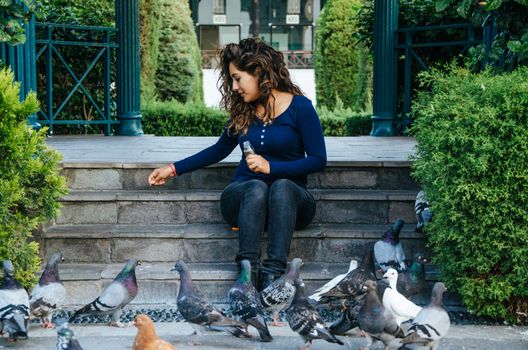 Beautiful smiling woman feeding pigeons in the park during the day at Friendship park in Surco, Lima - Peru