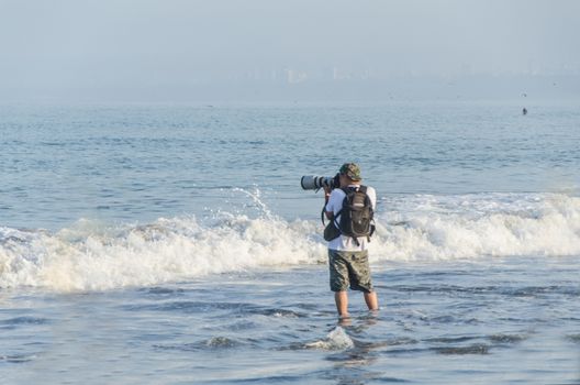 Young photographer with his professional camera taking pictures of boats in the sea, marine background for summer vacations and holiday travel concepts