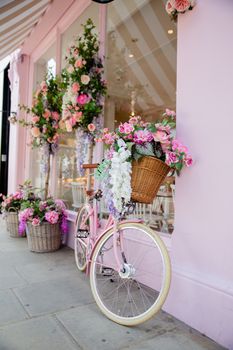 Portrait View of a Pink Bicycle Surrounded by Artificial Flowers Outside a Pink Cake Shop from London, UK