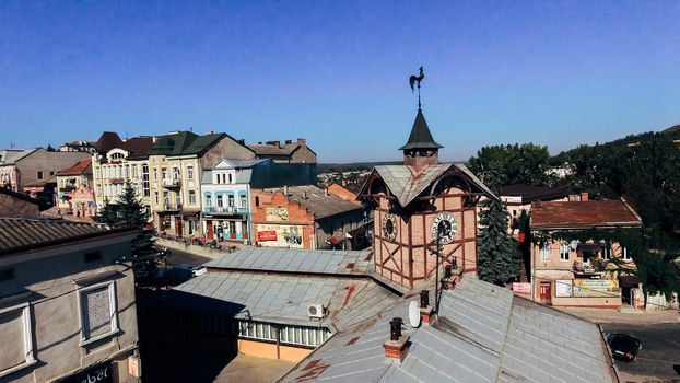 weather vane on the roof of an old house with a tower and a clock. Air view. View from above