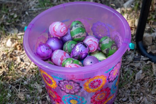 Bright pink and flowered easter basket with Easter egg hidden in brown leaves . High quality photo