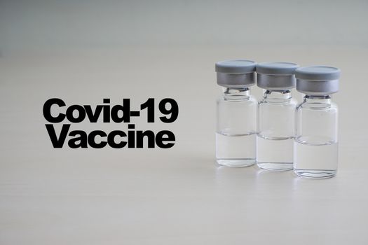 COVID -19 VACCINE text with vials on wooden background. Coronavirus or Covid-19 Vaccine concept