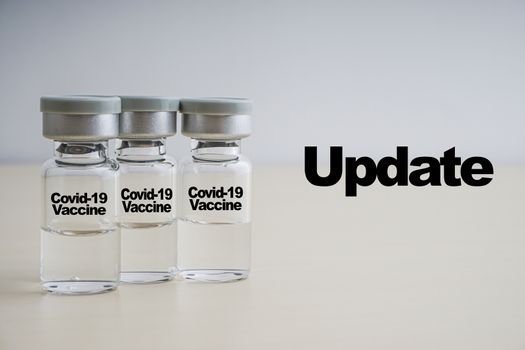 UPDATE text with vials on wooden background. Coronavirus or Covid-19 Vaccine concept
