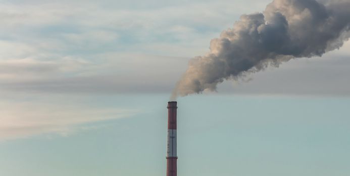 Panoramic shot of heating plant pipe that supply central heating system of the city. Smoke coming out of the pipes. Blue cloudy sky as a background. Industrial landscape. Barnaul, Russia.