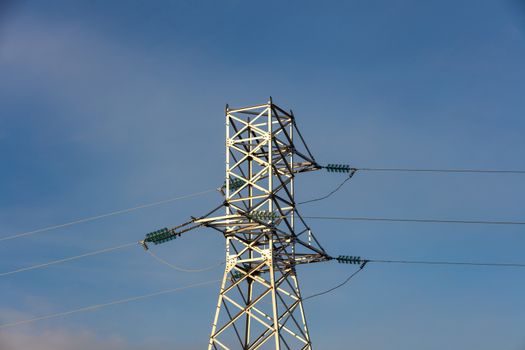 Low angle shot of high voltage electric tower and power lines in the city. Blue sky background. Barnaul, Siberia, Russia.