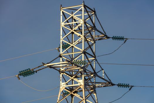 Close up low angle shot of high voltage electric tower and power lines in the city. Blue sky background. Barnaul, Siberia, Russia.