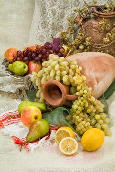 Old ceramic vase, pot and fruits on a fabric background