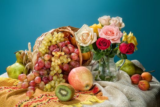 Wicker basket, ceramic vase and fruits on a studio background