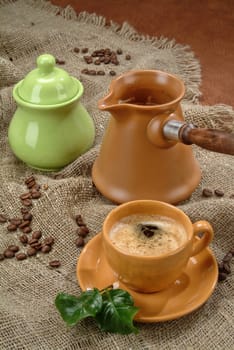 Cup of tea and a coffee pot on a fabric background