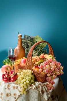 Wicker basket, ceramic vase and fruits on a studio background