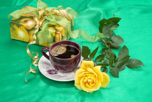 Goft box, cup of tea and rose on a fabric background