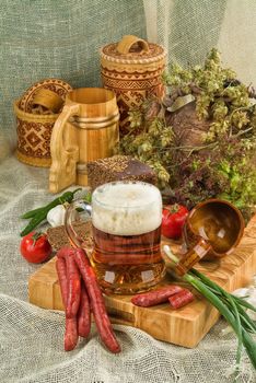 Mug of bier, sausages and greenery on a canvas background